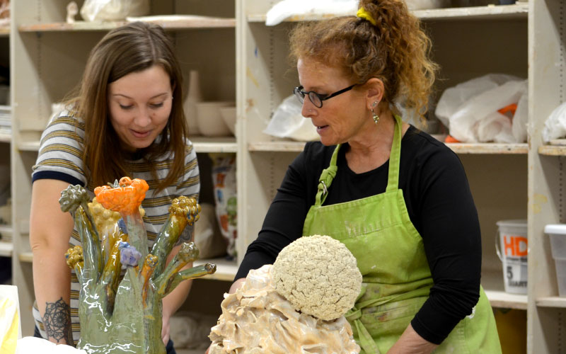Art student working with professor on a sculpture