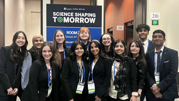 ASU students posing for a photo in front of a sign for the AAAS 2025 Annual Meeting. 