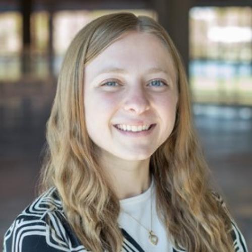 Samantha Harker with long blonde hair and blue eyes smiling at the camera wearing a black and white shirt